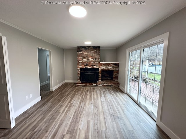 unfurnished living room with a brick fireplace, crown molding, and wood-type flooring