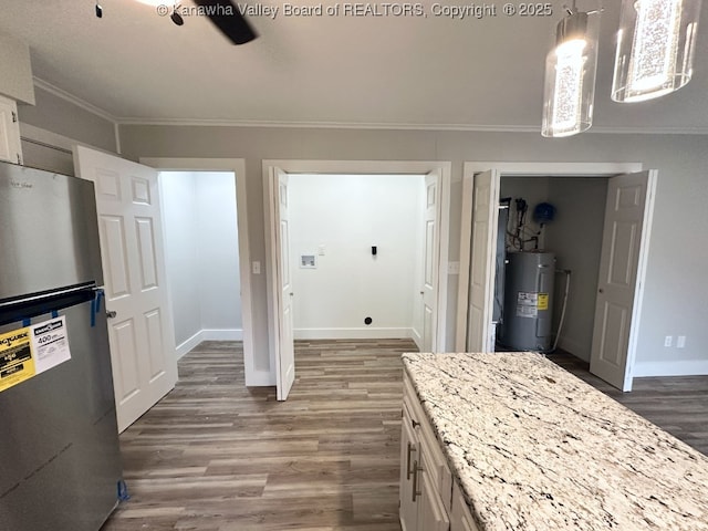 kitchen with electric water heater, stainless steel refrigerator, crown molding, white cabinets, and decorative light fixtures