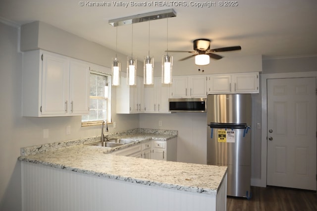 kitchen with decorative light fixtures, stainless steel appliances, sink, and white cabinetry