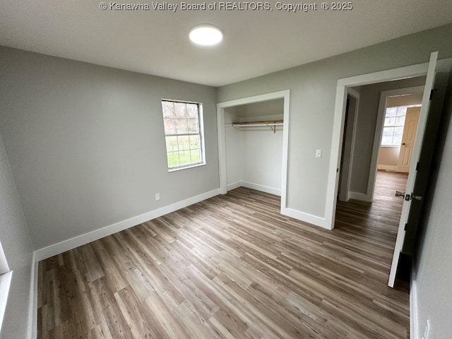 unfurnished bedroom featuring hardwood / wood-style floors, a closet, and multiple windows