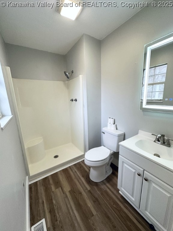 bathroom featuring hardwood / wood-style floors, a shower, toilet, and vanity