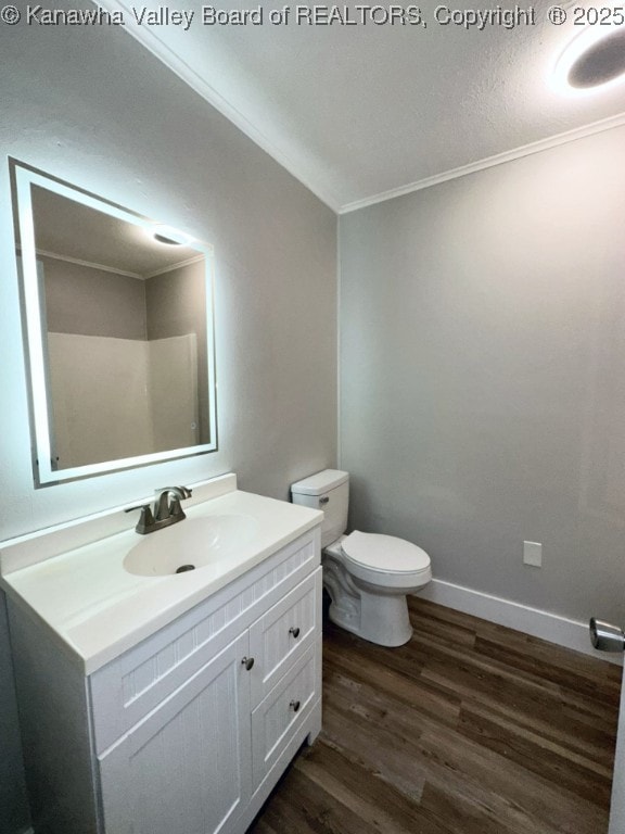 bathroom featuring toilet, hardwood / wood-style flooring, ornamental molding, and vanity