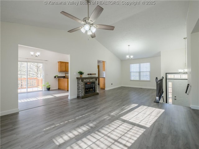 unfurnished living room with ceiling fan with notable chandelier, high vaulted ceiling, a fireplace, and hardwood / wood-style flooring