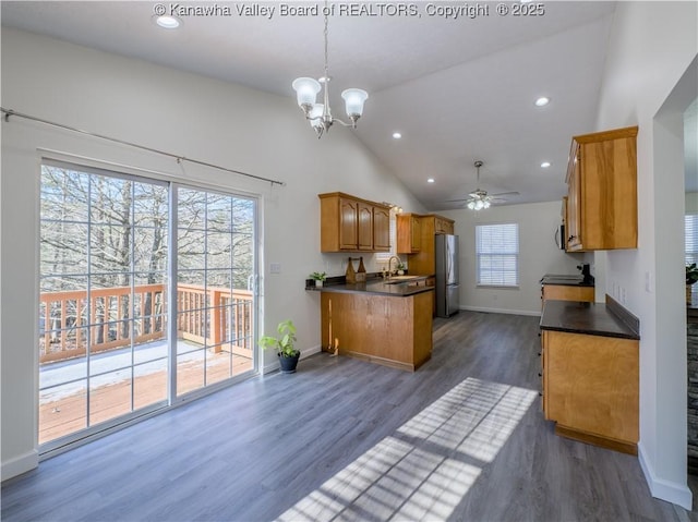 kitchen featuring dark hardwood / wood-style floors, hanging light fixtures, stainless steel fridge, ceiling fan with notable chandelier, and sink