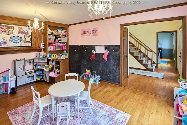 game room with an inviting chandelier, ornamental molding, and hardwood / wood-style flooring