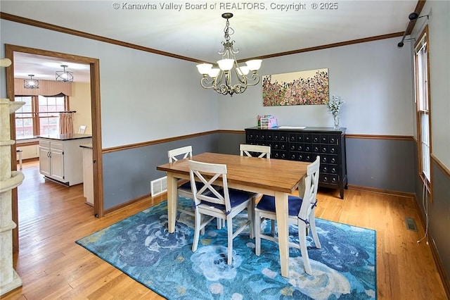 dining room featuring light hardwood / wood-style flooring, crown molding, and a chandelier