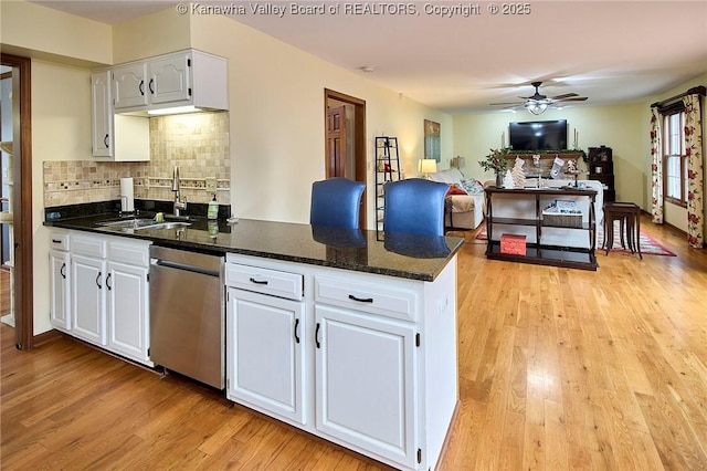 kitchen with white cabinetry, dark stone counters, light hardwood / wood-style flooring, stainless steel dishwasher, and tasteful backsplash