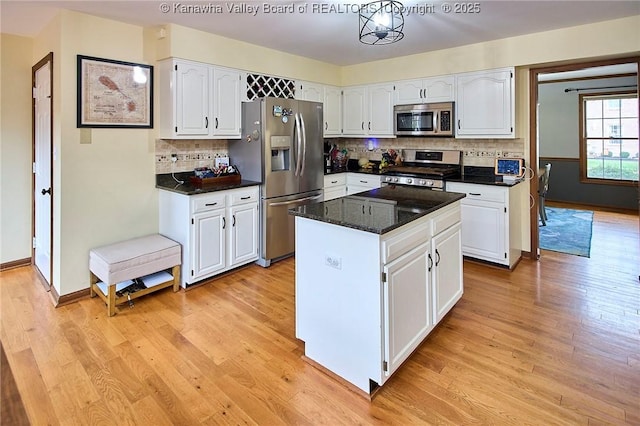 kitchen featuring stainless steel appliances, white cabinets, decorative backsplash, dark stone counters, and a kitchen island