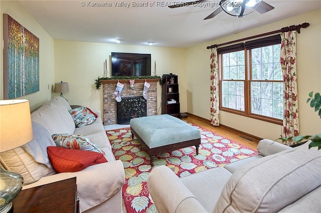 living room featuring ceiling fan, a brick fireplace, and hardwood / wood-style flooring