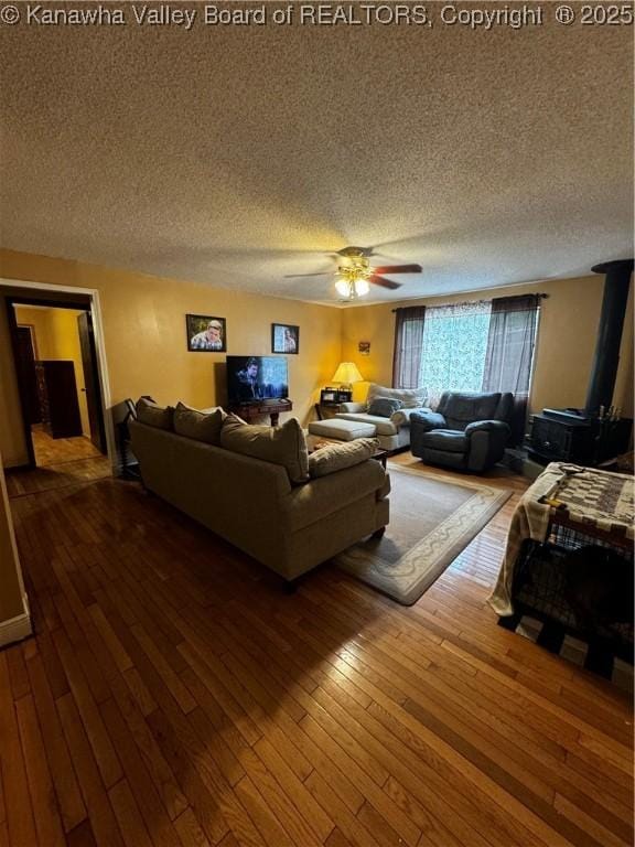 living room featuring wood-type flooring, a textured ceiling, and ceiling fan