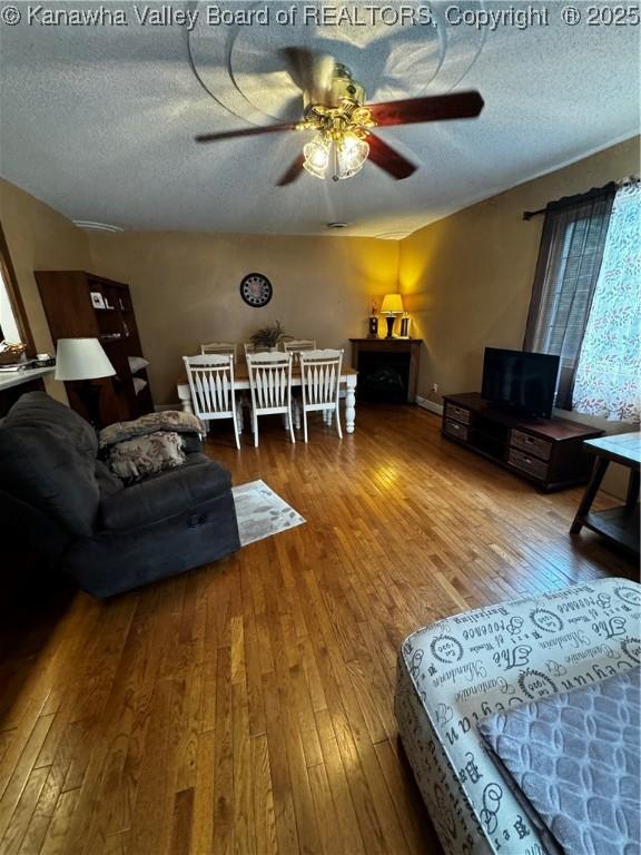 living room featuring a textured ceiling, ceiling fan, and wood-type flooring