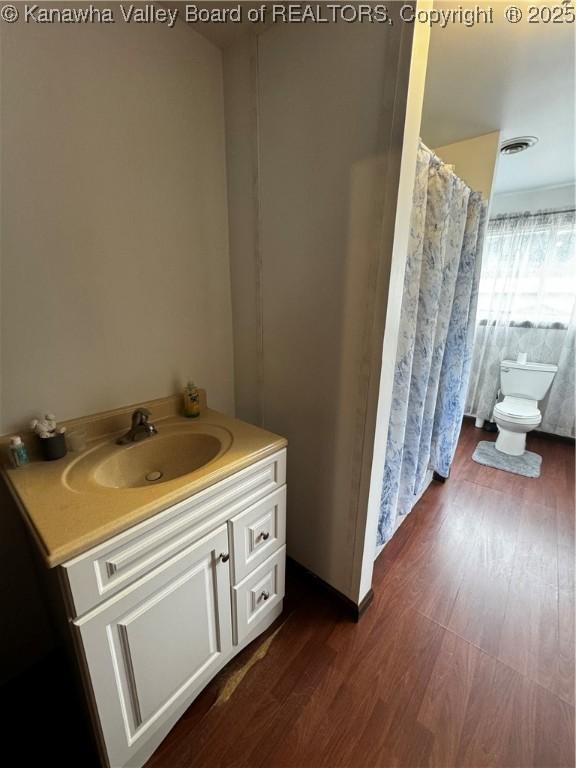 bathroom featuring toilet, vanity, and hardwood / wood-style floors