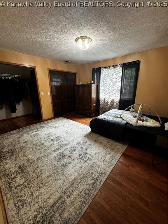 bedroom featuring a textured ceiling and dark hardwood / wood-style flooring