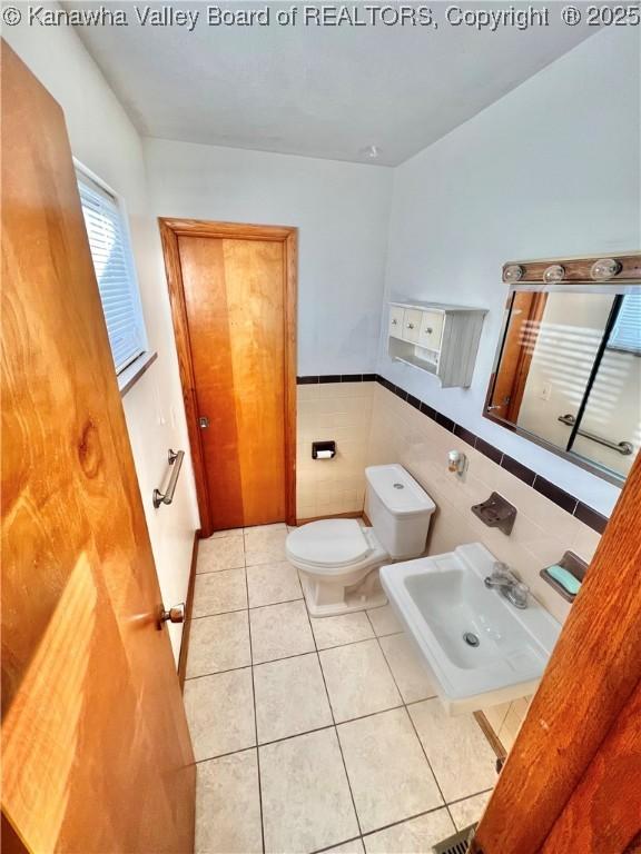 bathroom featuring sink, tile patterned floors, tile walls, and toilet