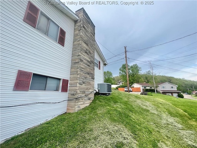 view of home's exterior featuring a lawn, stone siding, and cooling unit