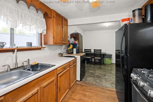 kitchen featuring electric range, black refrigerator, light hardwood / wood-style floors, sink, and gas range