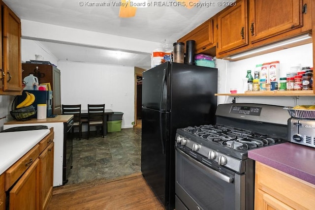 kitchen with black fridge, electric stove, stainless steel range with gas stovetop, and dark hardwood / wood-style flooring