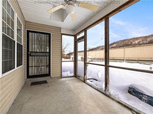 unfurnished sunroom with ceiling fan