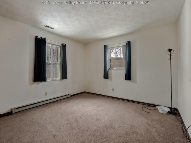 carpeted empty room featuring a baseboard heating unit and a textured ceiling