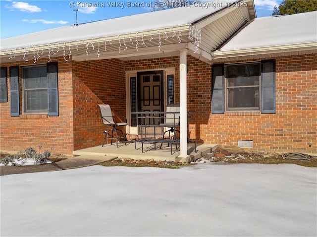 snow covered property entrance with a porch