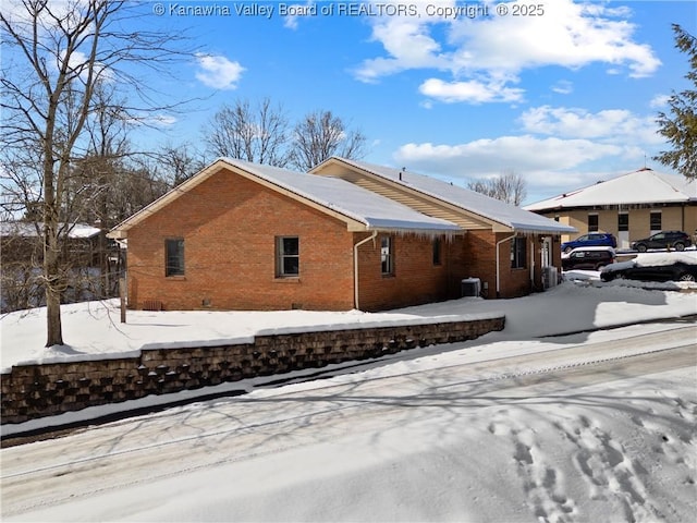 snow covered property with central AC