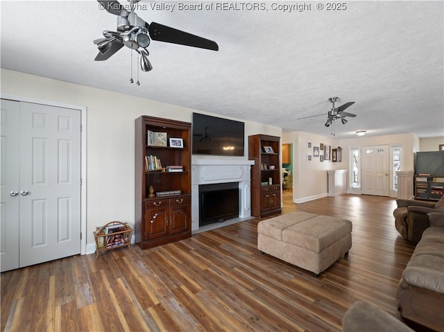 living room with ceiling fan, dark wood-type flooring, and a textured ceiling