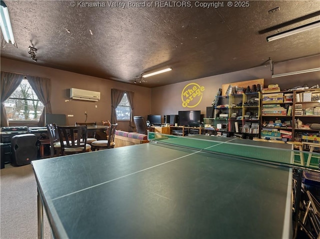 recreation room with an AC wall unit, a textured ceiling, and carpet