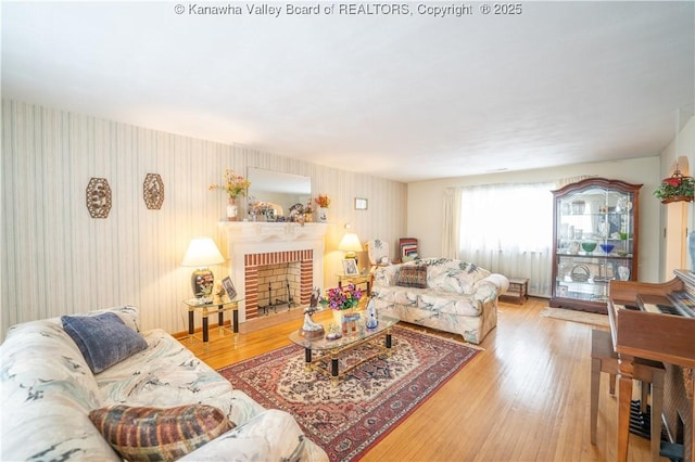 living room featuring a brick fireplace and wood-type flooring