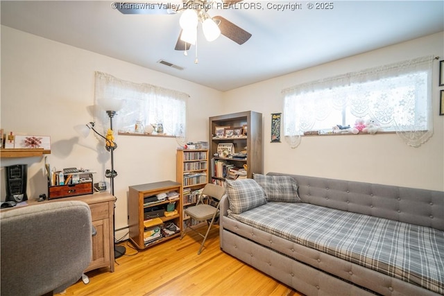 living room with ceiling fan, light wood-type flooring, and a baseboard heating unit