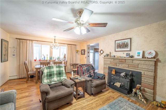 living room with ceiling fan with notable chandelier and light hardwood / wood-style flooring