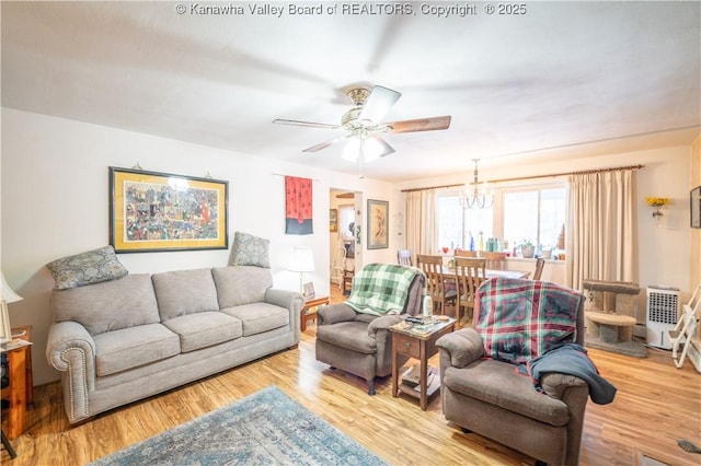 living room with ceiling fan with notable chandelier and light hardwood / wood-style floors