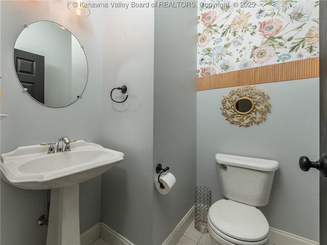 bathroom with toilet, sink, and tile patterned floors