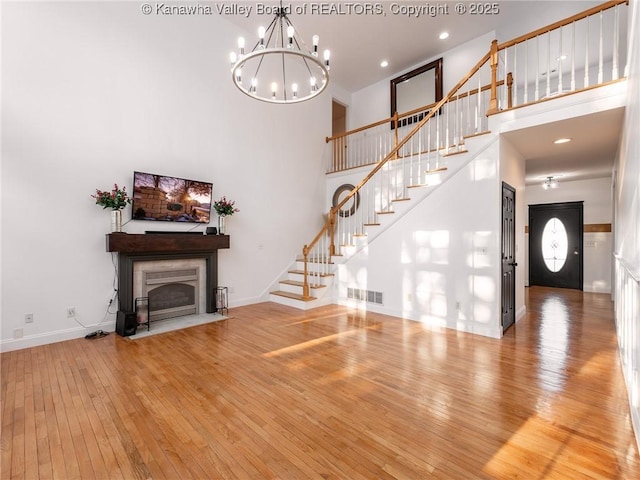 unfurnished living room featuring a high ceiling, hardwood / wood-style floors, and a chandelier