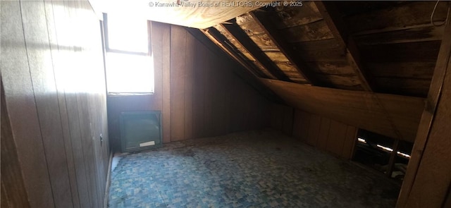 bonus room featuring vaulted ceiling and wooden walls