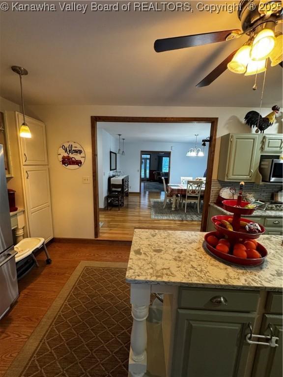 kitchen featuring hardwood / wood-style flooring, ceiling fan, stainless steel appliances, tasteful backsplash, and light stone countertops