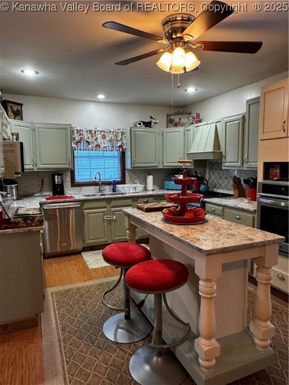 kitchen featuring appliances with stainless steel finishes, a center island, tasteful backsplash, light hardwood / wood-style floors, and sink