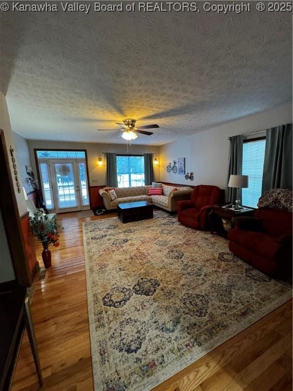 living room with hardwood / wood-style flooring, a textured ceiling, and ceiling fan