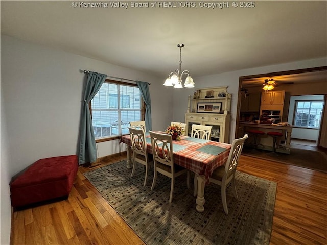 dining space featuring ceiling fan with notable chandelier and wood-type flooring