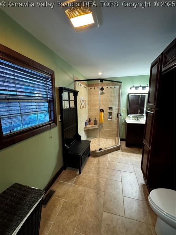 bathroom featuring toilet, a shower with shower door, and vanity