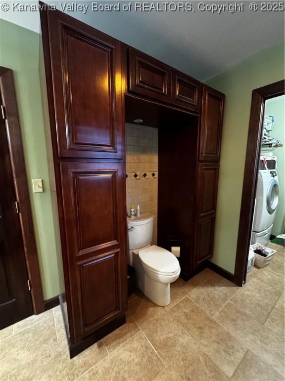 bathroom featuring toilet and washer / dryer