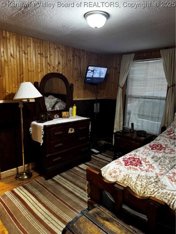 bedroom featuring wooden walls and a textured ceiling