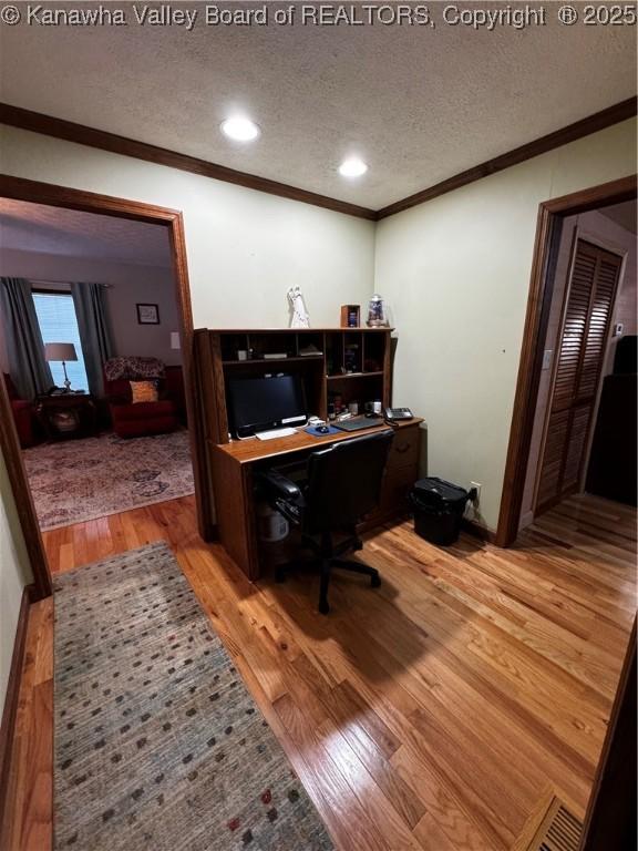 office featuring wood-type flooring, ornamental molding, and a textured ceiling