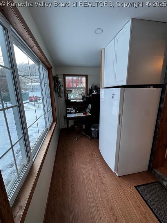 kitchen featuring wood-type flooring, white cabinets, white fridge, and a healthy amount of sunlight