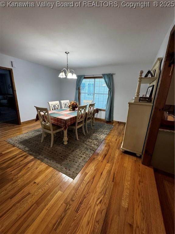 dining space with wood-type flooring and an inviting chandelier