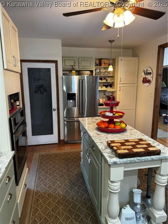 kitchen with ceiling fan, stainless steel appliances, dark hardwood / wood-style flooring, pendant lighting, and light stone counters