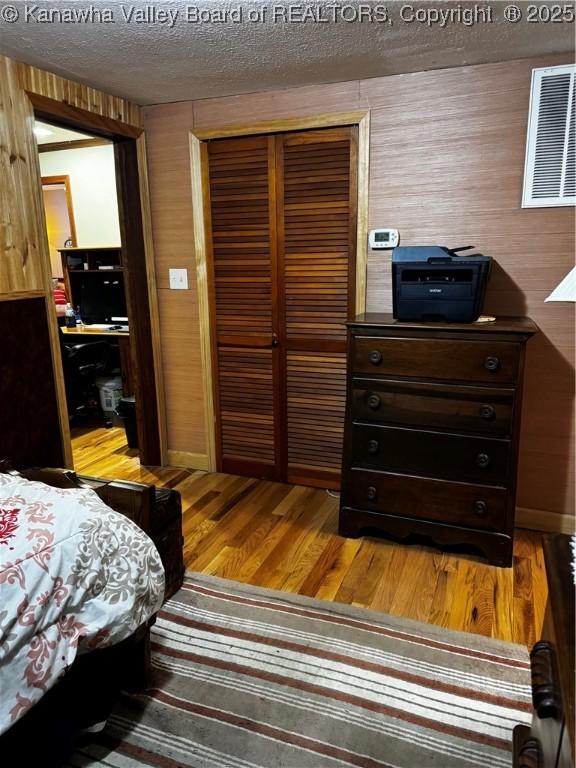 bedroom featuring hardwood / wood-style flooring, a textured ceiling, and a closet