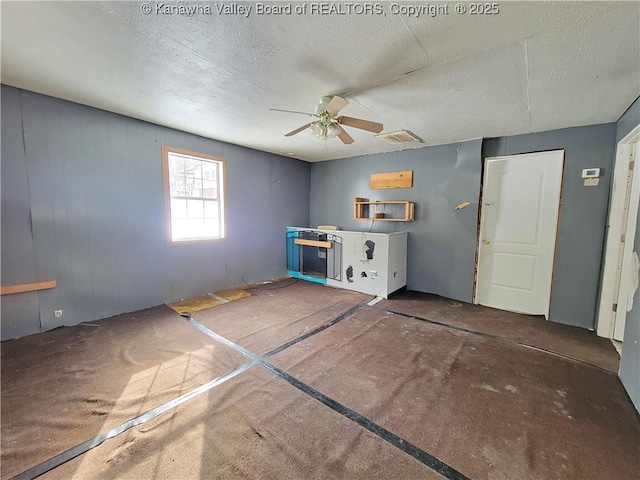 misc room with a textured ceiling, ceiling fan, and dark carpet