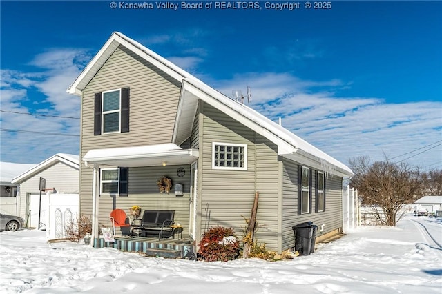 snow covered rear of property featuring covered porch