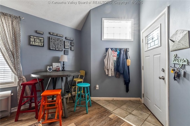 tiled foyer entrance with vaulted ceiling and a textured ceiling