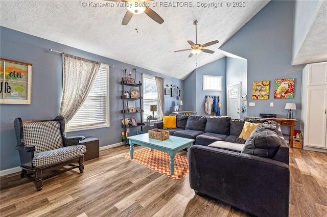 living room featuring light hardwood / wood-style floors, a textured ceiling, ceiling fan, and vaulted ceiling